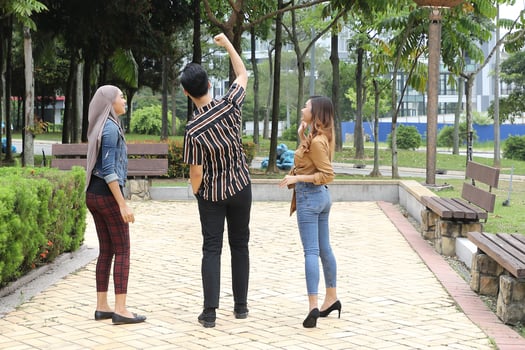 Young Asian Malay man woman outdoor green park walk talk discuss mingle sign show photo
