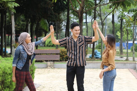 Young Asian Malay man woman outdoor green park walk talk discuss mingle happy joy high five photo