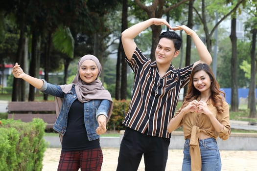 Young Asian Malay man woman outdoor green park walk talk discuss mingle happy joy hand on head hart shape hand sign photo