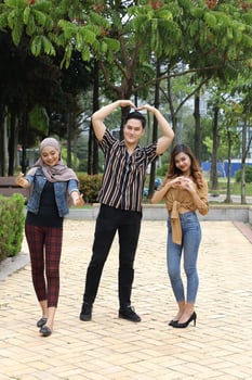 Young Asian Malay man woman outdoor green park walk talk discuss mingle sign show photo