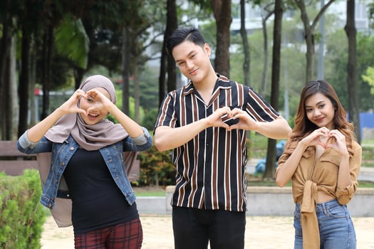 young Asian Malay man woman outdoor green park walk talk discuss mingle happy joy hart shape hand sign photo