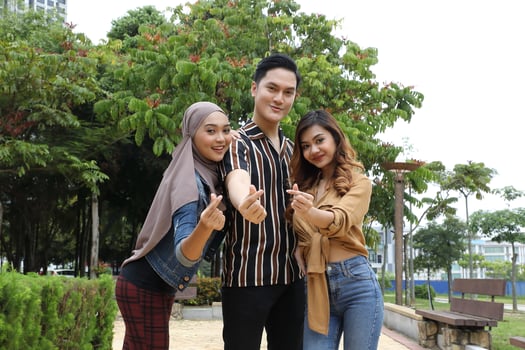 Young Asian Malay man woman outdoor green park walk talk discuss mingle sign show photo