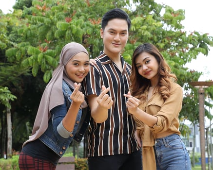Young Asian Malay man woman outdoor green park walk talk discuss mingle sign show photo