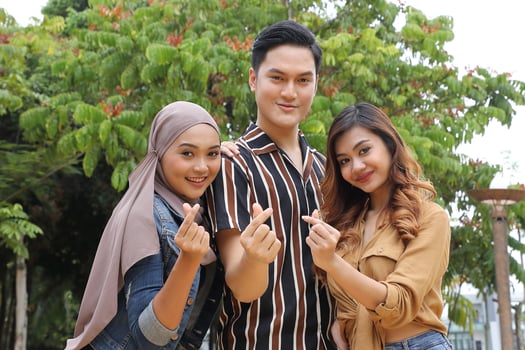 Young Asian Malay man woman outdoor green park walk talk discuss mingle happy joy hart love shape hand sign photo