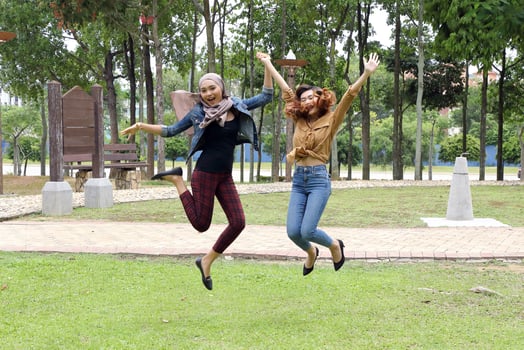 Young Asian Malay man woman outdoor green park joy happy jump in the air photo
