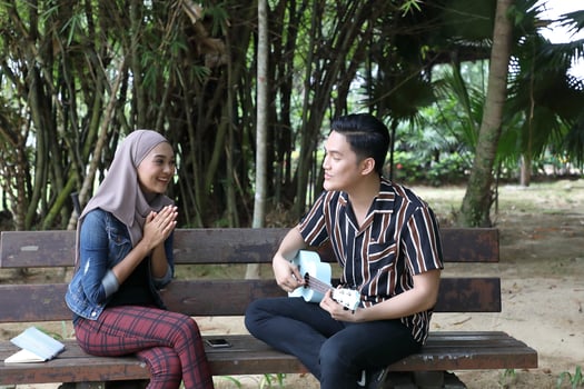 Young Asian Malay man woman outdoor green park walk talk discuss mingle photo