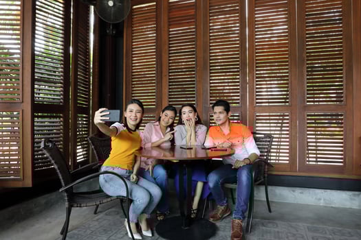 Group young asian malay man woman at rustic wooden cafe table meet talk discuss business study selfie self portrait hand smart phone photo