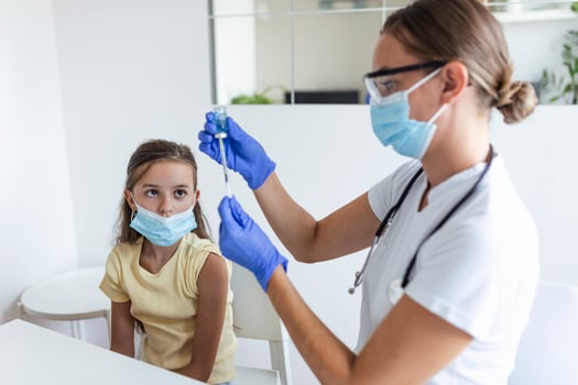 Antiviral immunization campaign concept.Doctor vaccinating girl. Girl in medical masks getting vaccinated against covid-19, doctor giving injection of coronavirus vaccine at hospital. photo