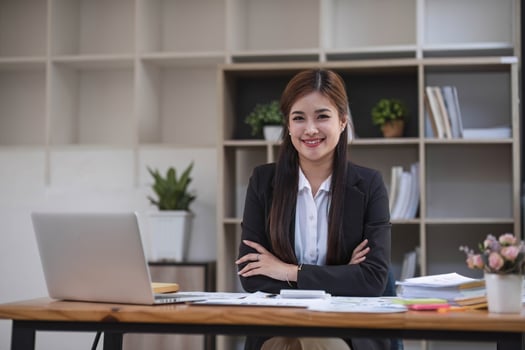 Beautiful asian businesswoman sitting at office desk, smiling and looking at camera. photo