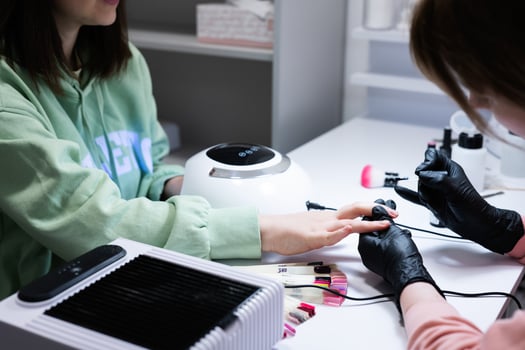 Manicure master working with female client in beauty salon. Manicurist makes woman nail. photo