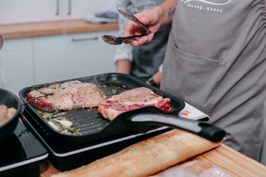 cooking steaks in a pan. cooking beef at the culinary master class. the hands of the chef in black gloves. photo