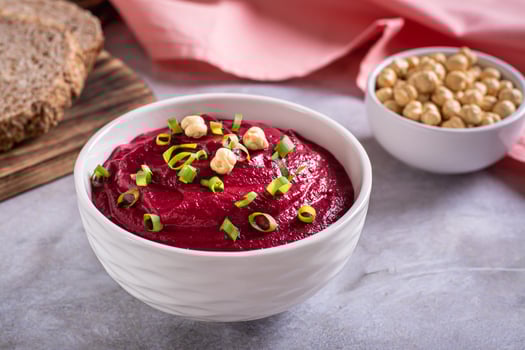Beetroot hummus in a bowl, bread and chickpeas on the table photo