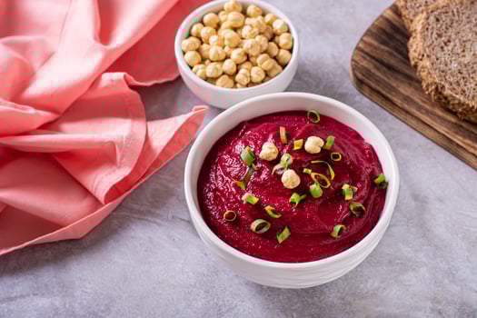 Bowl of vegetable beetroot hummus with chickpeas and herbs on the table photo