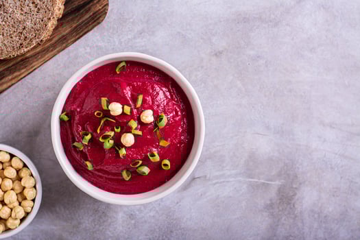 Beetroot hummus in a bowl, bread and chickpeas on the table top view photo