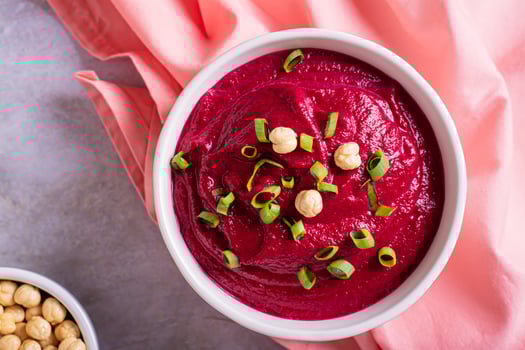 Close up of beetroot hummus in a bowl and chickpeas on the table top view photo