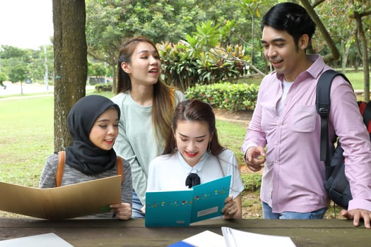 Young asian malay chinese man woman outdoor on park bench table study talk discuss point laptop file book photo