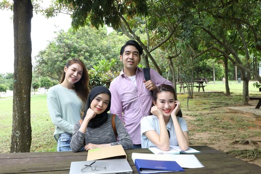Young asian malay chinese man woman outdoor on park bench table study talk discuss point laptop file book happy pose look forward photo