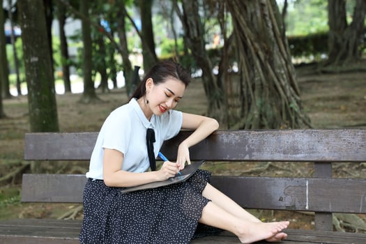 Young asian chinese woman outdoor on park bench hold file book folder read write see smile photo