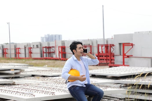 Asian man malay worker engineer management hard safety hat helmet at construction site holding plan talking on phone photo
