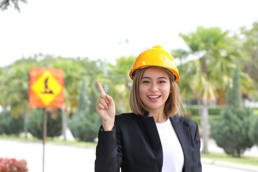woman Malay Chinese worker engineer management hard safety hat helmet at construction site pointing up photo
