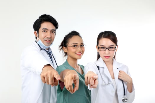 Young asian malay chinese male female doctor on white background pointing finger at camera focus on finger blurry face photo