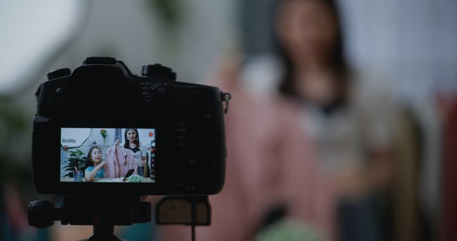 Young Beautiful Asian woman live streaming at clothes shop on digital camera photo