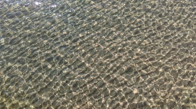 sand drifts underwater with sun glare on the water photo