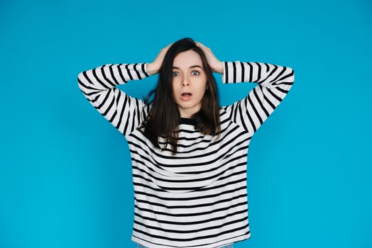 Excited Woman in Striped Sweater Celebrating Super Sale with Hands Raised - Energetic and Joyful Female Shopper Expressing Happiness - Isolated Blue Background - Perfect for Advertising and Promotions photo