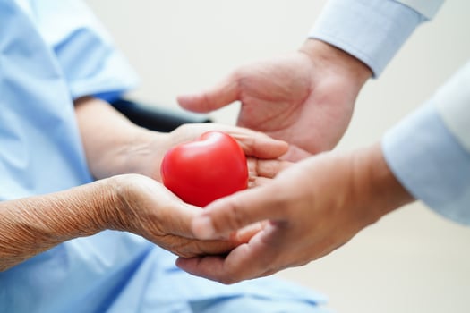 Asian man doctor give red heart to elderly woman patient for good health in hospital. photo