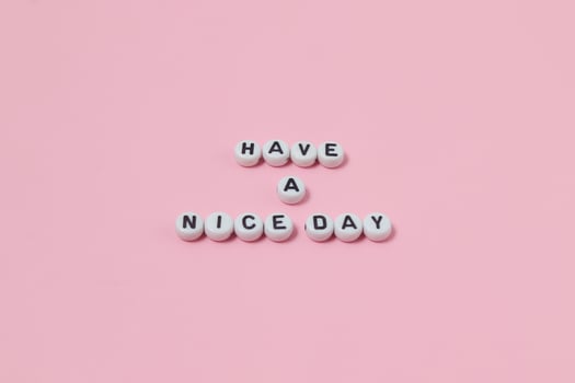 Top view of Have a nice day quotes made out of beads on pink background. motivation and success concept photo