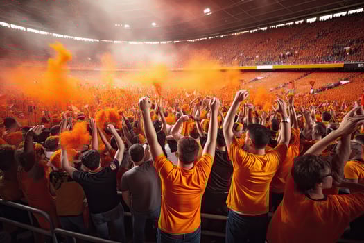 Football fans in orange tshirts at the stands of the stadium, Fans celebrating and cheering inside a stadium, photo