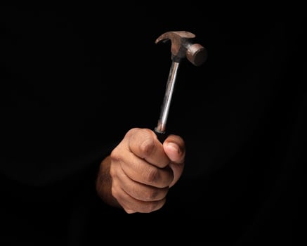 Asian male dark skinned single hand fist finger on black background holding using hammer photo