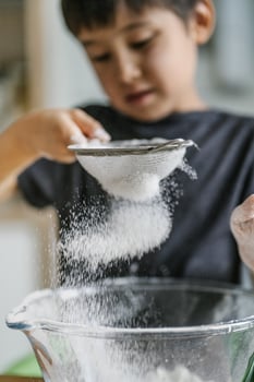 The child cooks in the kitchen. Sifts the flour. photo