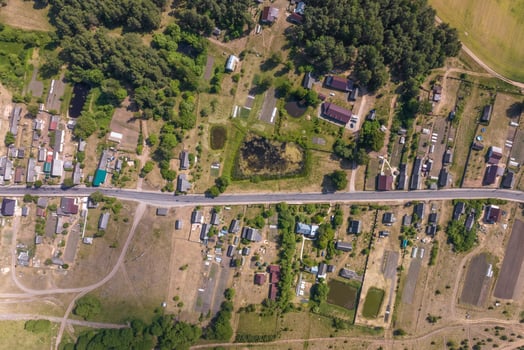 panoramic aerial view of eco village with wooden houses, gravel road, gardens and orchards photo