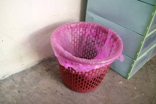 Red trash can covered with pink plastic photo