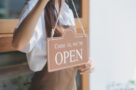 Young entrepreneur holding open sign on glass door at cafe photo