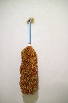 A duster with red yellow feathers, hangs on the wall photo