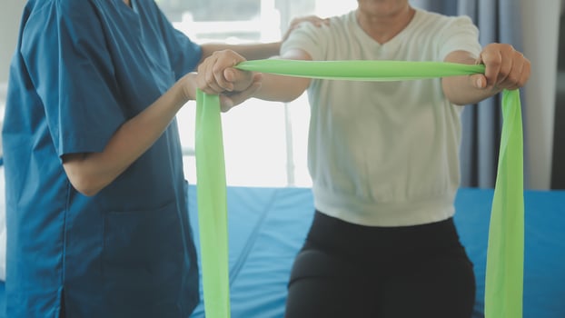 Happy senior woman doing exercise at home with physiotherapist. Old retired lady doing stretching arms at home with the help of a personal trainer during a rehabilitation session. photo