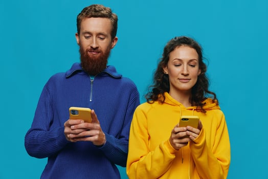 Woman and man cheerful couple with phones in their hands crooked smile cheerful, on blue background. The concept of real family relationships, talking on the phone, work online. photo