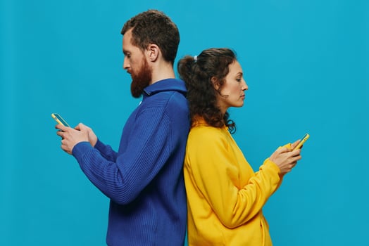 Woman and man cheerful couple with phones in their hands crooked smile cheerful, on blue background. The concept of real family relationships, talking on the phone, work online. photo
