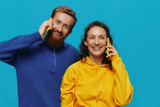 Woman and man cheerful couple with phones in their hands crooked smile cheerful, on blue background. The concept of real family relationships, talking on the phone, work online. photo