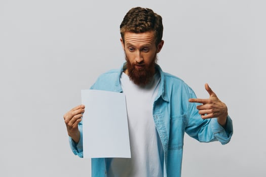 Portrait of an adult male on a gray background with a white sheet of paper in his hands for your design and text, layout, copy space, space for text, finger pointing photo