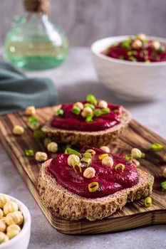 Homemade rye bread sandwiches with beetroot hummus and herbs on a cutting board vertical view photo