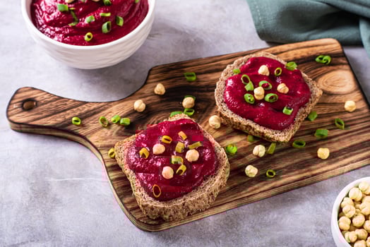 Appetizing rye bread bruschettas with beetroot hummus and chives on a cutting board photo