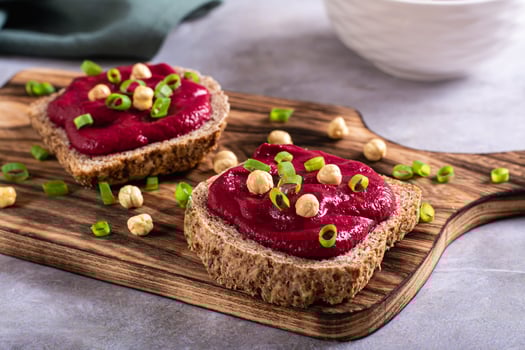 Homemade rye bread sandwiches with beetroot hummus and herbs on a cutting board photo