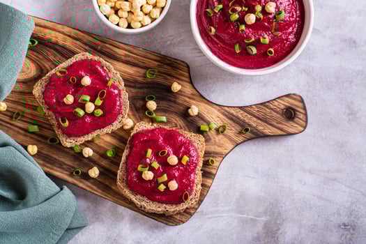 Homemade rye bread sandwiches with beetroot hummus and herbs on a cutting board top view photo