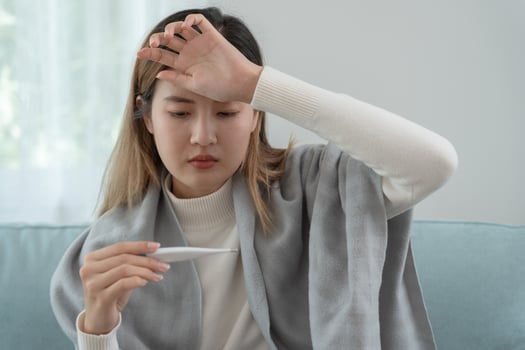 Young Asian woman having high fever while checking body temperature, female sneezing and runny nose with seasonal influenza, allergic, digital thermometer, virus, coronavirus, illness, respiratory photo