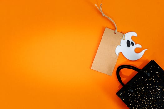Halloween sale banner with label, ghost and bag on orange background. photo