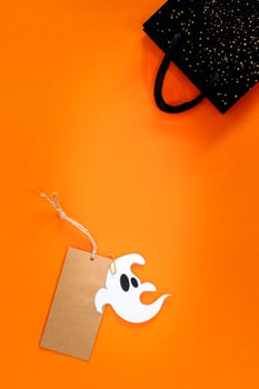 Halloween sale banner with label, ghost and bag on orange background. photo