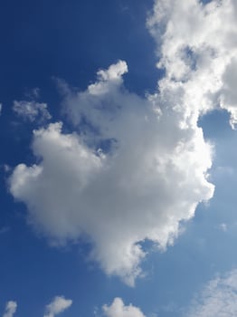 White clouds in the blue sky. Beautiful bright blue background. Light cloudy, good weather. Curly clouds on a sunny day. photo